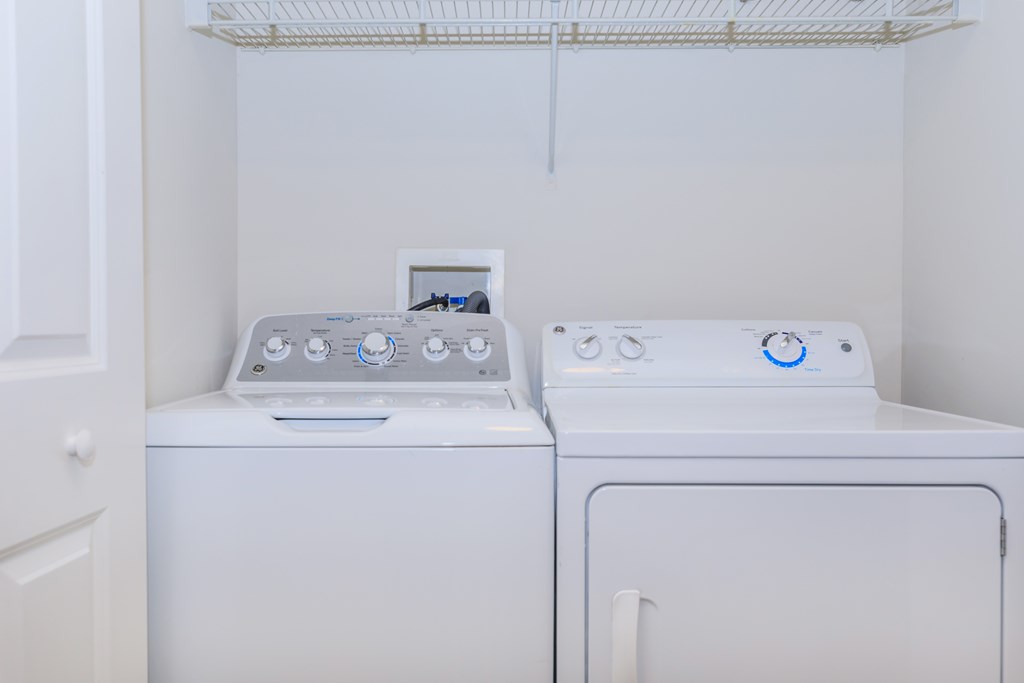 Two white front loading washing machines in a small laundry room.