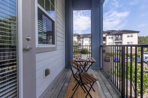 A balcony with a table and chairs overlooking a parking lot.