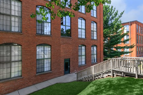 A red brick building with a green door and a wooden staircase.
