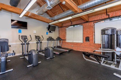 A gym with a variety of exercise equipment including treadmills, stationary bikes, and weight machines.