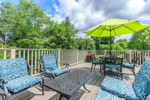 A yellow umbrella sits on a patio table surrounded by chairs.