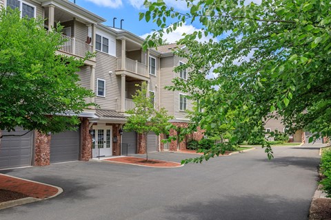 A large apartment complex with a driveway and trees.