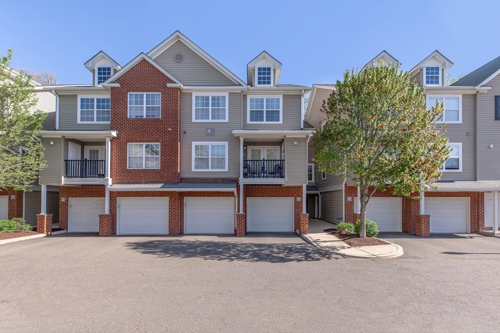 A row of townhouses with garages and trees in front.