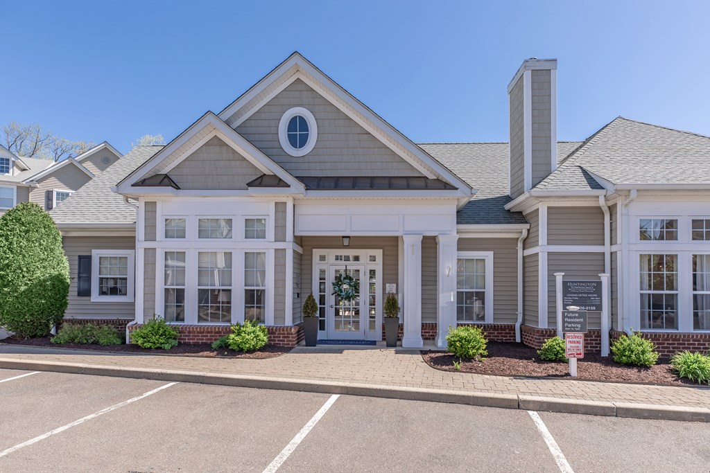 A building with a grey roof and a white door is surrounded by a parking lot.