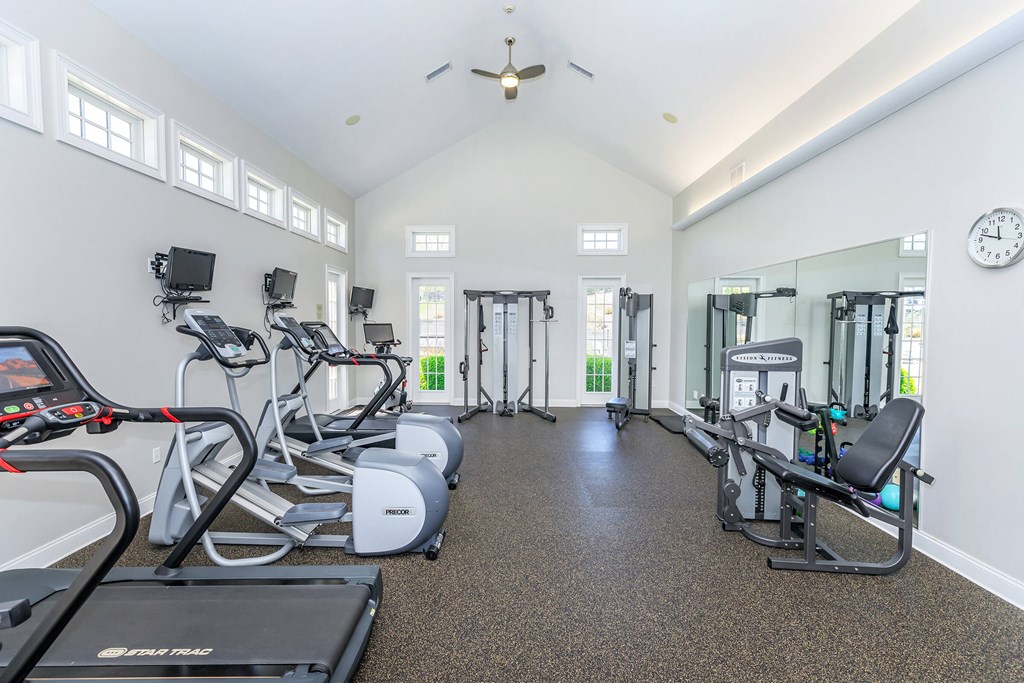A spacious gym with treadmills, elliptical machines, and a weight bench.