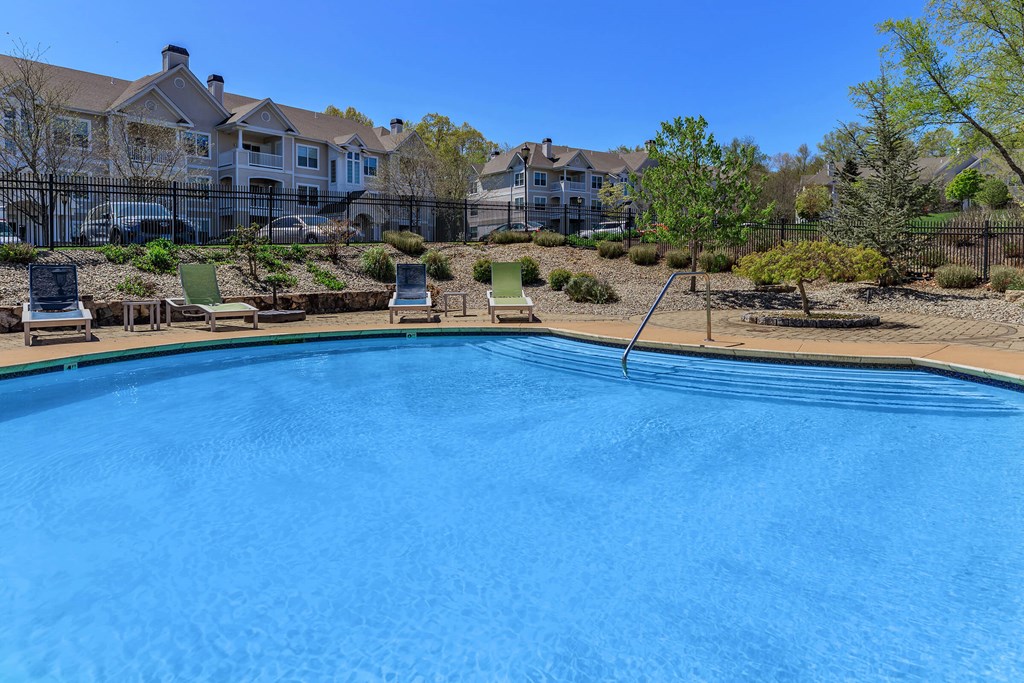 A blue swimming pool with a residential building in the background.