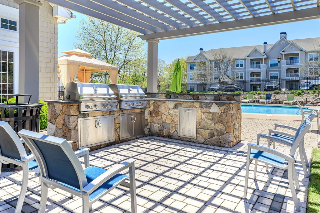 A patio with a stone wall and a grill.
