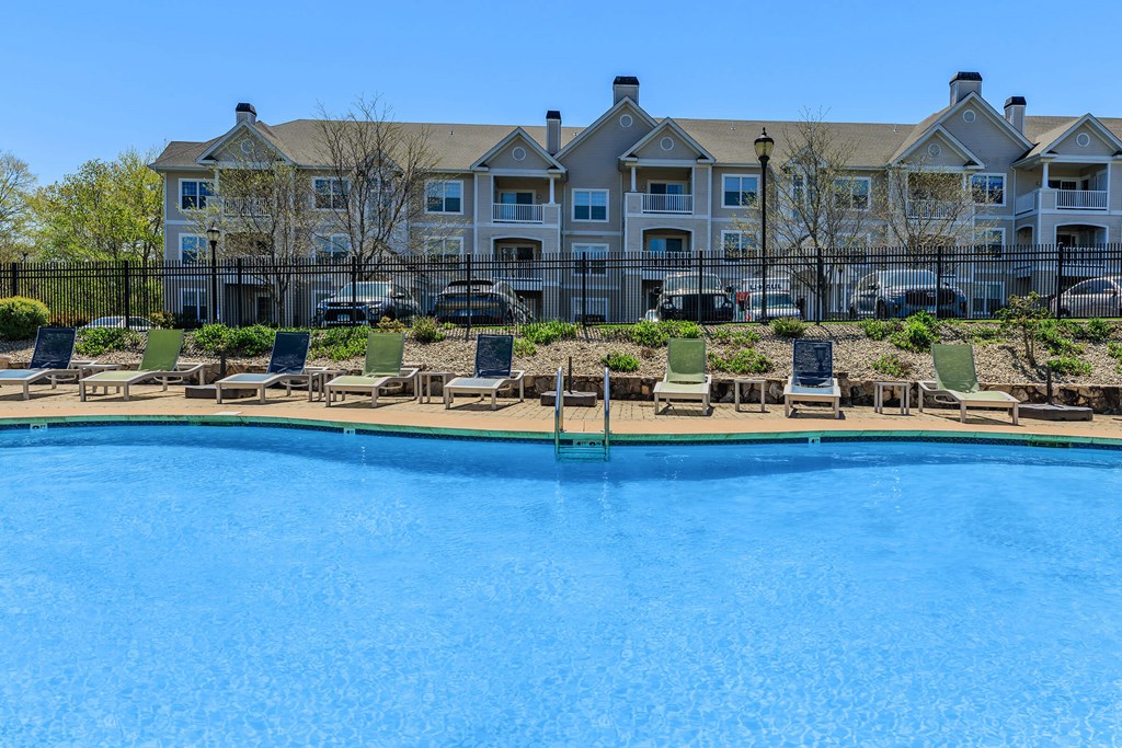 A large swimming pool in front of a multi-story apartment building.