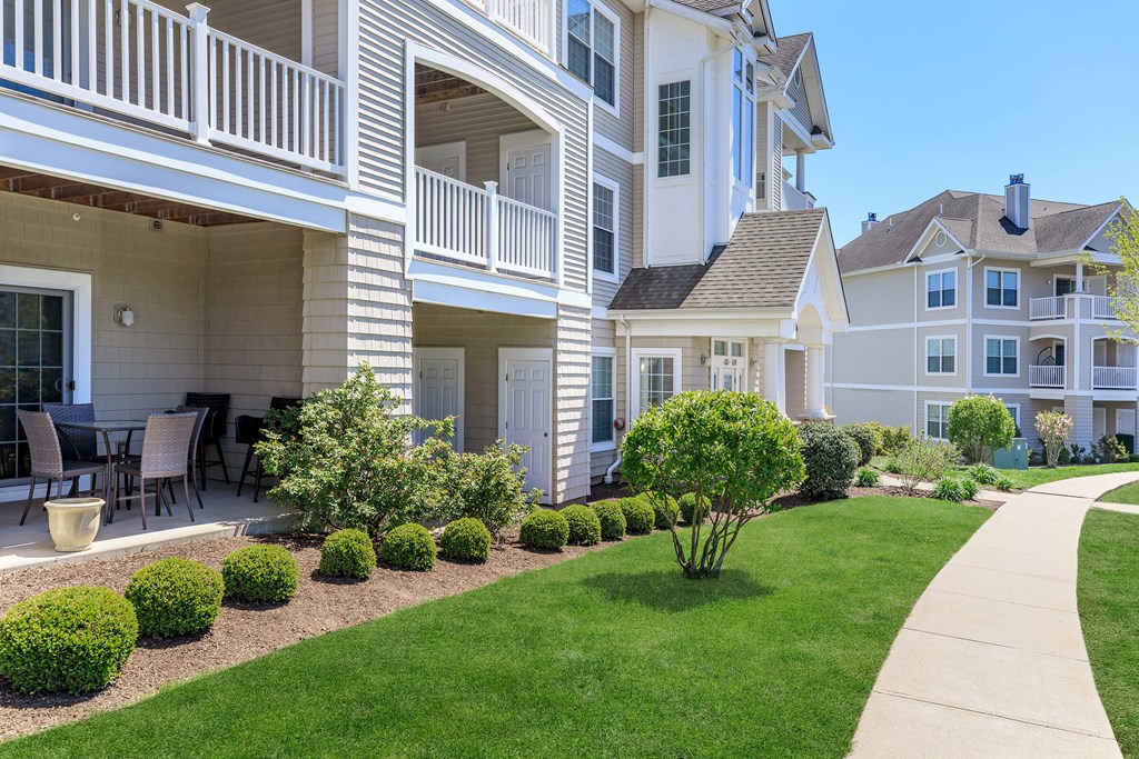 A white building with a balcony and a green lawn in front.