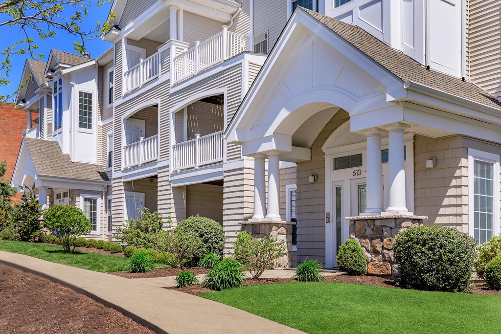 A white two-story house with a balcony and a front porch.