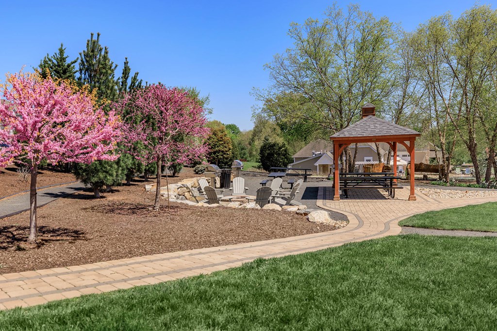 A gazebo is surrounded by a grassy area and trees.