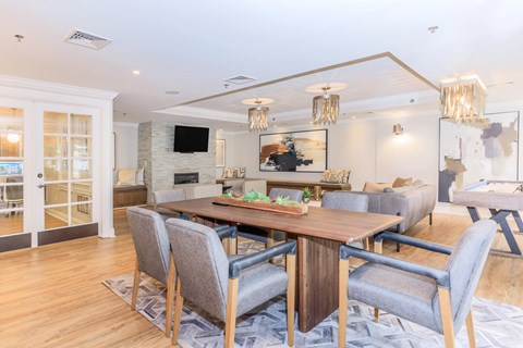 A modern dining room with a wooden table and grey chairs.