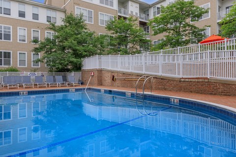 A swimming pool in front of a building with a white fence around it.