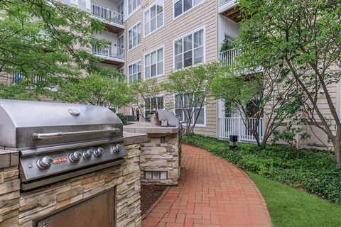 A brick BBQ is in front of a stone wall.