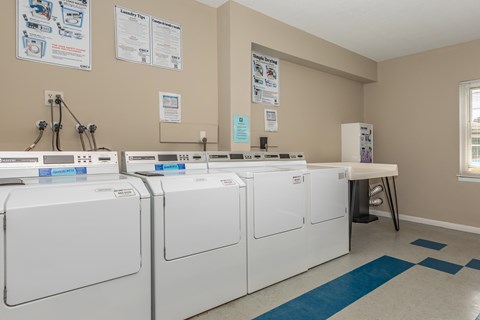 A laundromat with washers and dryers and instructions on the wall.