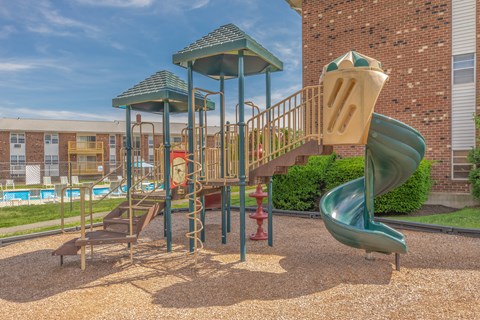 A playground with a green slide and a red fire hydrant.