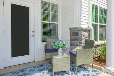 A patio with a chair, table and flowers.