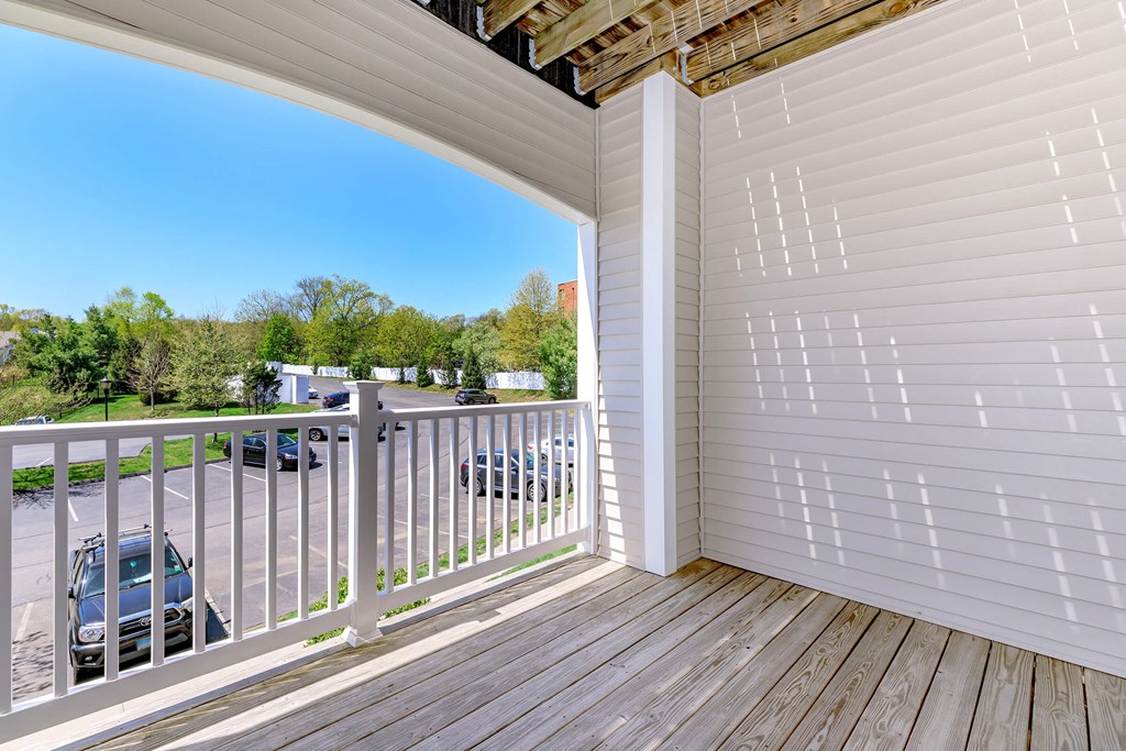 A balcony with a white railing and wooden floor.