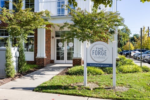 A sign for The Forge Glassworks is in front of a building.