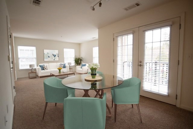 A dining room with a glass table surrounded by chairs.