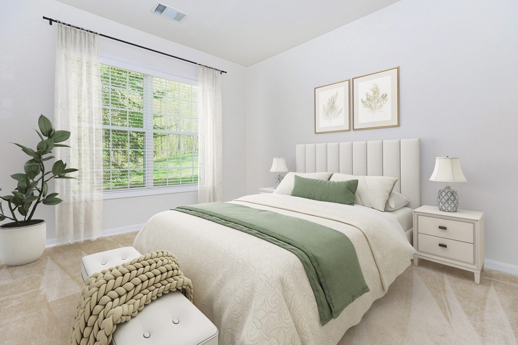A bedroom with a large bed, a potted plant, and two framed pictures on the wall.