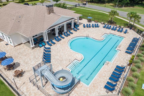 A large outdoor pool with a slide and sun loungers.