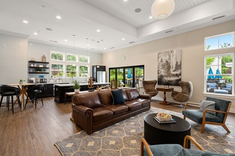 A living room with a brown leather couch and a coffee table with a bowl of fruit on it.