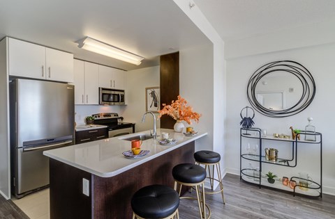 a kitchen with an island and stools and a stainless steel refrigerator