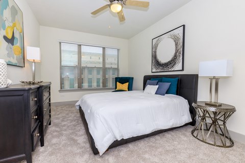 A bedroom with a large bed, a dresser, and a ceiling fan.
