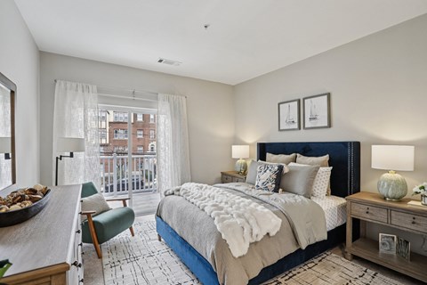 A bedroom with a large bed and a chair by the window.