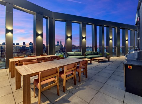 a communal dining table on a balcony with a view of the city