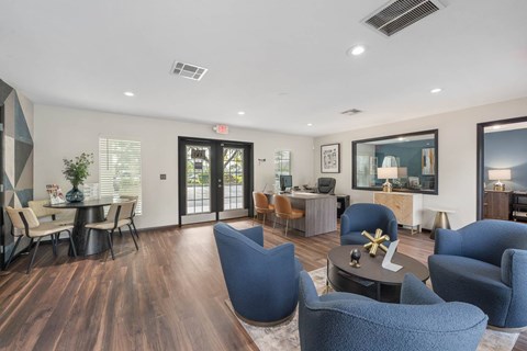 A living room with blue chairs and a wooden floor.