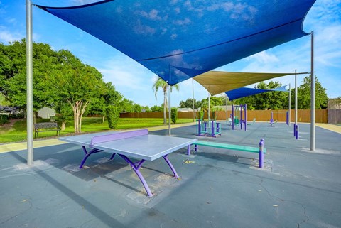 A playground with a purple table and a blue shade structure.