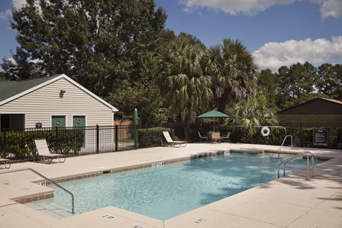 A pool surrounded by trees and a house.