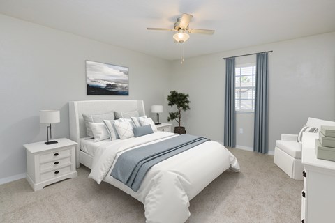 A bedroom with a large bed, a ceiling fan, and a nightstand with a lamp.