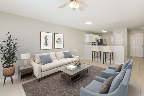 A living room with a grey couch, a coffee table, and a ceiling fan.