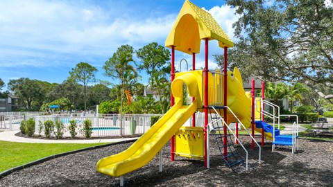 A playground with a yellow slide and a blue slide.