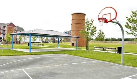 A basketball court with a hoop and a blue pole.