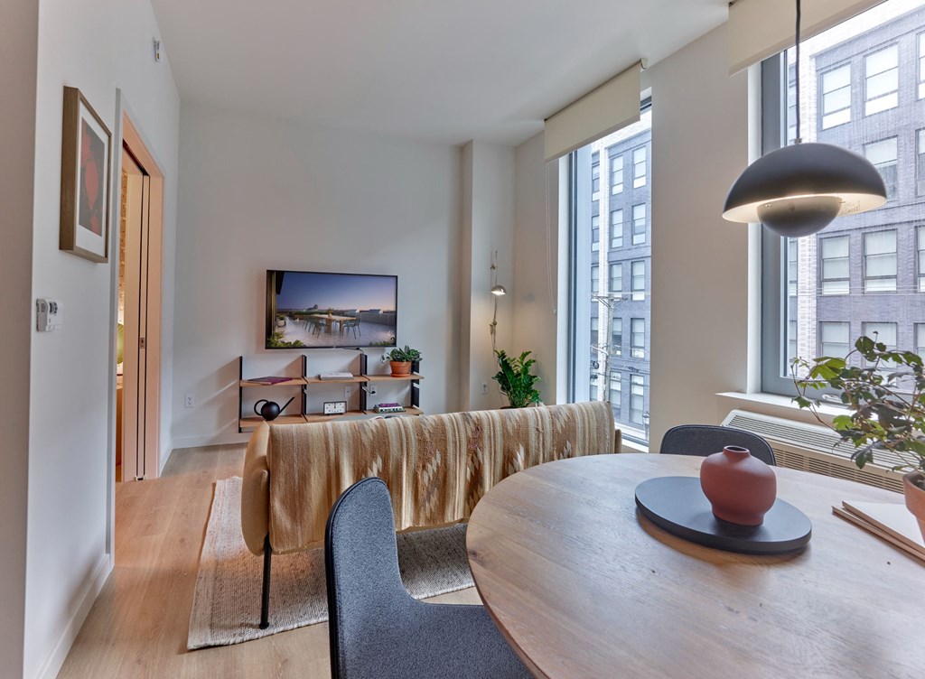 a dining room with a table and chairs and a living room with large windows