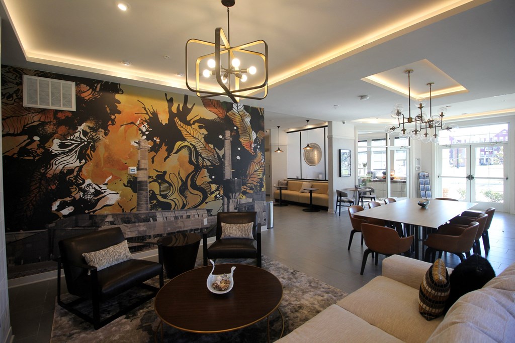 A living room with a large painting on the wall and a chandelier hanging from the ceiling.