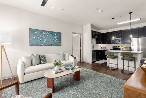 A modern living room with a white couch and a painting on the wall.