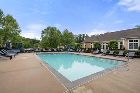 A large swimming pool surrounded by lounge chairs and trees.