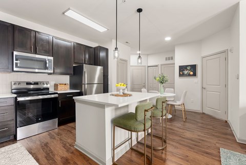 A modern kitchen with dark brown cabinets and a white island.