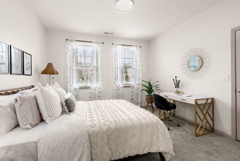 A bedroom with a large bed and a desk with a chair.