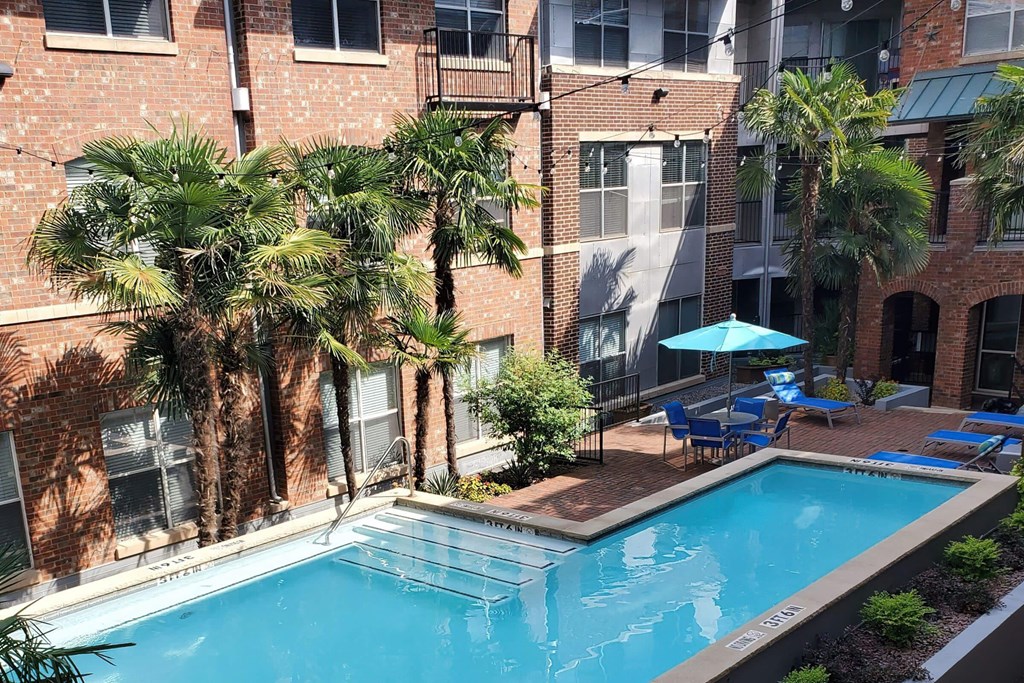 a swimming pool in front of a building with palm trees