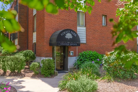 The entrance to the Forest Park Leasing Office is framed by green shrubbery.