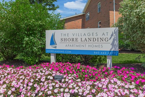 A sign for The Villages at Shore Landing Apartment Homes stands in front of a building.