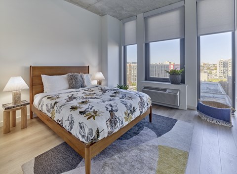 a bedroom with a bed and a window with a city view