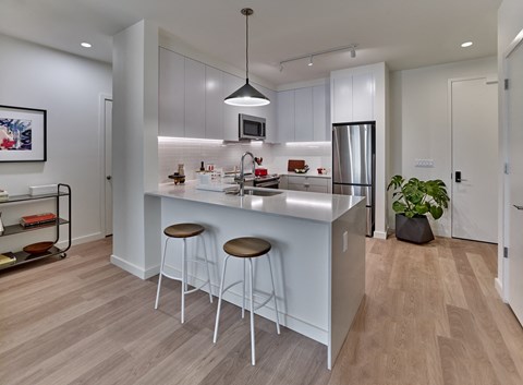 A modern kitchen with white cabinets and a wooden floor.