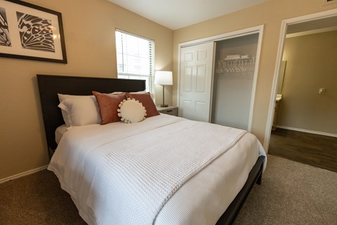 A bedroom with a bed, pillows, and a carpeted floor.